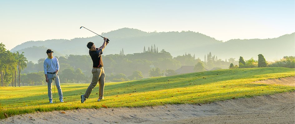 two people golfing with man swinging wide